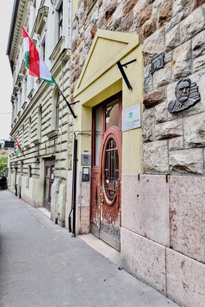 A building with a stone facade, a red door, and a flag. - Buda Bliss Garden Budapest (Budapest)