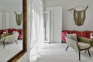 A room with a large mirror, wicker furniture, a red patterned sofa, and a macrame wall hanging. - Buda Bliss Garden Budapest (Budapest)