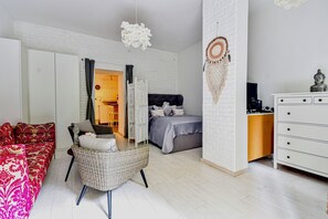 A modern bedroom with a bed, a sofa, a chair, a dresser, and a wall with a dreamcatcher. - Buda Bliss Garden Budapest (Budapest)