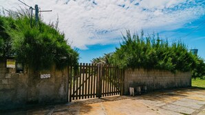A gated entrance with a stone wall, a wooden gate, and a sign with the number 1855. - Casa P na Areia com Piscina a em Lu s Correia (Luis Correia)