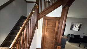 Una scala in legno con corrimano e una porta sul fondo.
