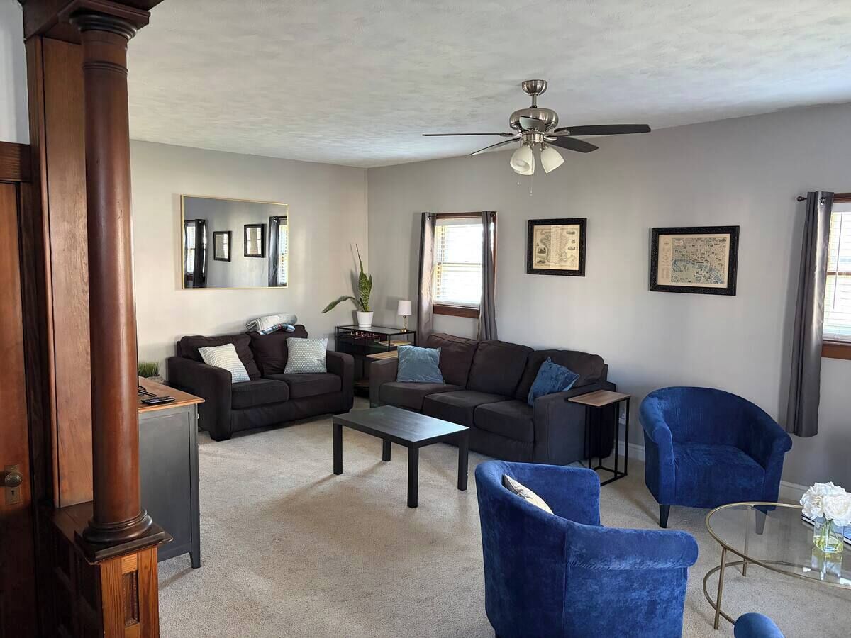 A living room with a ceiling fan, dark-colored sofas, a coffee table, and a blue armchair.