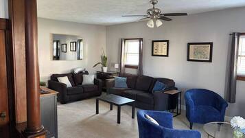 A living room with a ceiling fan, dark-colored sofas, a coffee table, and a blue armchair.