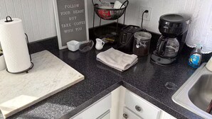 Una cucina con portasciugamani in carta, una macchina da caffè, un tostapane, un lavello e una bacheca.
