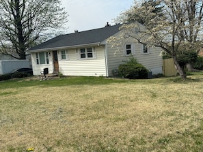 A single-story house with a dark roof, white siding, and a front porch.