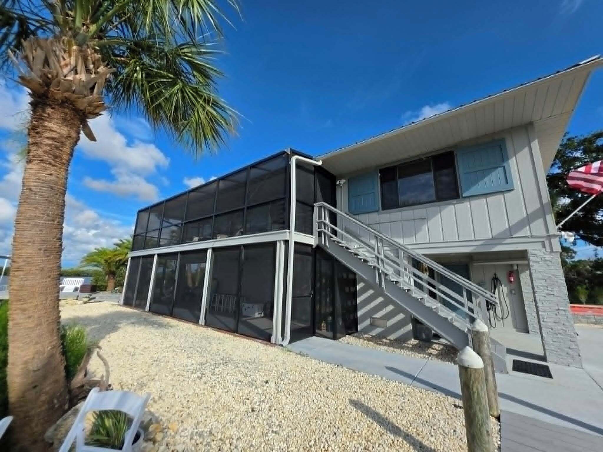 A modern building with a glass facade, a staircase, and a palm tree.