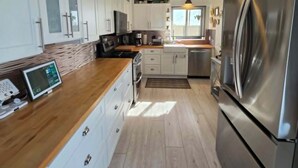 Une cuisine moderne avec des armoires blanches, des appareils en acier inoxydable et un comptoir en bois.