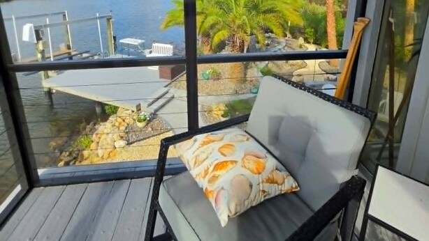 Un balcon avec vue sur une étendue d’eau, des palmiers et un quai.