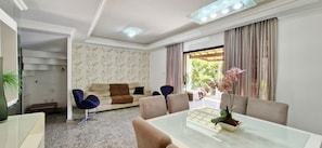 Ein modernes Wohnzimmer mit einer Couch, Sesseln, einem Esstisch und einer Treppe, die in einen anderen Raum führt.