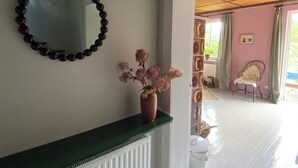 Ein Zimmer mit Heizkörper, Spiegel und einer Vase mit Blumen auf einem Regal.