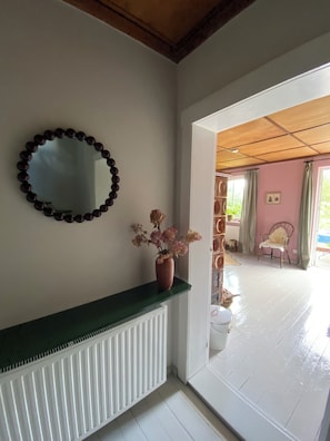 Ein Zimmer mit Heizkörper, Spiegel und einer Vase mit Blumen auf einem Regal.