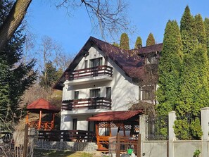 Un b âtiment à deux étages doté d’un balcon, d’un espace extérieur aménagé et couvert, et d’un mur en pierre.