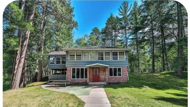 A two-story house with a front porch, a garage, and a pathway leading to the entrance.