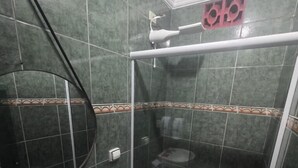 Une salle de bain avec douche, toilettes et lavabo.
