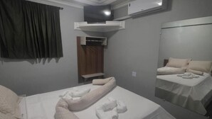 Une chambre d’hôtel équipée d’un lit, d’un miroir, d’une armoire et d’un appareil de climatisation.