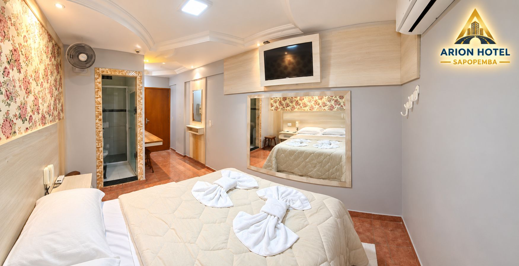 Una habitación de hotel con cama, televisión, espejo y zona de ducha.
