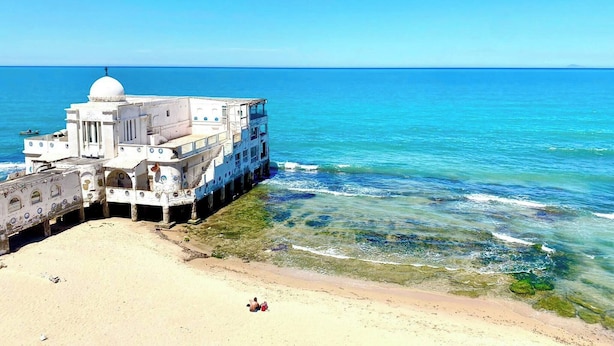 A white building with a dome, located on a sandy beach with clear blue water. - Elegant Beachfront Apartment in La Marsa With Panoramic Sea Views (La Marsa)