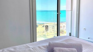 A hotel room with a bed, two towels, a view of the sea, and a balcony. - Elegant Beachfront Apartment in La Marsa With Panoramic Sea Views (La Marsa)