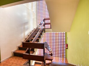 Eine Treppe mit Holzboden und Metallgeländer, die zu einem Raum mit grüner Wand und einem Wanddekor führt.
