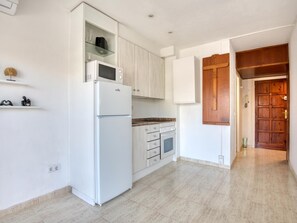 Eine Küche mit weißen Schränken, einer eingebauten Mikrowelle, einem Herd und einem Kühlschrank.