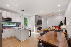 A modern kitchen with white cabinets, a built-in microwave, and a large island. - Suite Duplex @Downtown Unit B 6 Br/6 Bath (Houston)