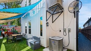 Un cortile con patio, area salotto esterna, un condizionatore d'aria di grandi dimensioni e una ventola.