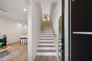 A modern interior with a staircase, a dining area, and a black door. - Suite Duplex @Downtown Unit B 6 Br/6 Bath (Houston)