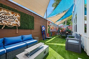 An outdoor patio with a sofa, a table, and a mural on the wall. - Suite Duplex @Downtown Unit B 6 Br/6 Bath (Houston)