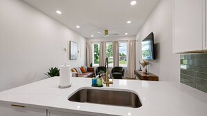 Una cucina moderna con isola centrale, luci a incasso nel soffitto e vista sull'area soggiorno.