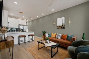 Un salon moderne avec un canapé, une table basse et des tabourets de bar.