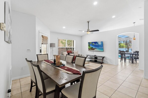 A dining area with a wooden table, chairs, and a ceiling fan.