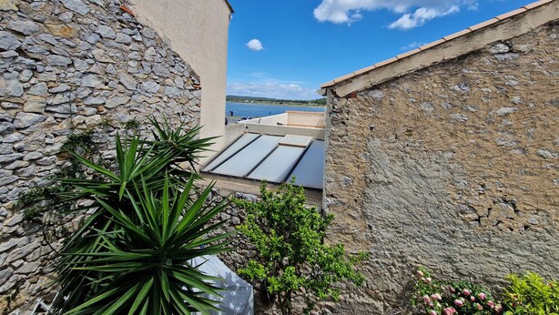 A courtyard with stone walls, a view of the sea, and a plant in the foreground. - Large house in the heart of the village of Gruissan (Gruissan)