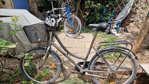 A stationary bicycle with a basket and a seat, parked on a stone pathway. - Large house in the heart of the village of Gruissan (Gruissan)