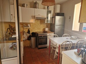 Una cocina compacta con estufa, horno, refrigerador y una mesa de comedor con sillas.