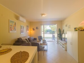 Ein Wohnzimmer mit einer Couch, einem Esstisch und einer Küchenzeile mit Schränken und einer Arbeitsfläche.