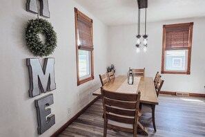 Ein Essbereich mit einem Holztisch, Stühlen, einer Chandelierleuchtre und einem 'WELCOME'-Schild an der Wand.