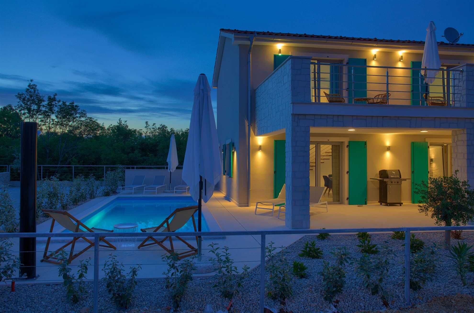 A modern two-story house with a swimming pool, outdoor seating, and a barbecue area.
