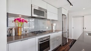 A modern kitchen with stainless steel appliances, a built-in oven, and a coffee maker. - Charming Apartment Gastown Downtown FIFA (Vancouver)