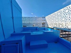 A rooftop pool area with blue-tiled steps and a decorative white lattice fence. - One-bedroom apartment with two beds, a bathroom, and a kitchen (Santo Domingo)