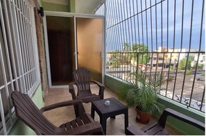Ein Balkon mit Blick auf eine Straße, eine Schiebetür und ein Blumentopf.