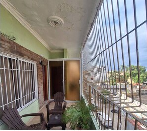 A balcony with a view of the street, a chair, a small table, and a potted plant. - Studio with a bed, bathroom, kitchen and a private balcony. (Santo Domingo)
