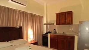 Una camera d'albergo con un letto, una scrivania, angolo cottura e frigorifero.