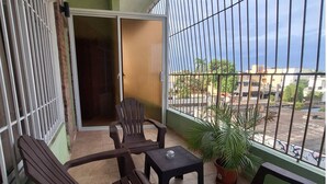 Un balcone con vista sulla strada, una porta scorrevole e una pianta in vaso.