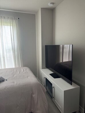 A bedroom with a bed, a TV on a white cabinet, and a window with curtains. - Perfect private 1-bedroom shared house with AC in enjoyable Angleton (Angleton)