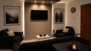 A modern room with a flat-screen TV, two framed pictures, a clock, a table with a candle, and a sofa. - Centrally located apartment, which allows your pet. (Mendoza)