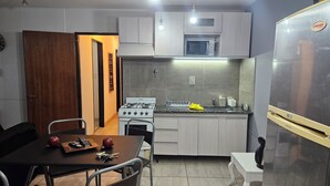A compact kitchen with a gas stove, microwave, and a refrigerator. - Centrally located apartment, which allows your pet. (Mendoza)