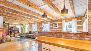 A rustic interior with exposed wooden beams, a wooden counter, and a seating area with a sofa and chairs. - The Magic Cottage: Artsy Nashville Escape w/ Hot Tub, Sleeps 10, & Near Downtown (Nashville)