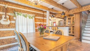 A rustic dining area with a wooden table, chairs, and a hanging guitar. - The Magic Cottage: Artsy Nashville Escape w/ Hot Tub, Sleeps 10, & Near Downtown (Nashville)