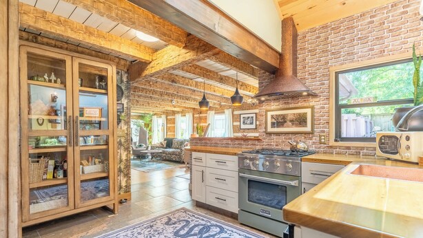 A kitchen with a brick wall, wooden cabinets, a stove, and a retro radio. - The Magic Cottage: Artsy Nashville Escape w/ Hot Tub, Sleeps 10, & Near Downtown (Nashville)