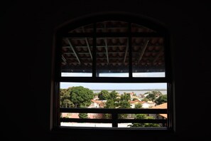 Ein Fenster mit Blick auf ein Wohngebiet, ein Gewässer und eine hügelige Landschaft.